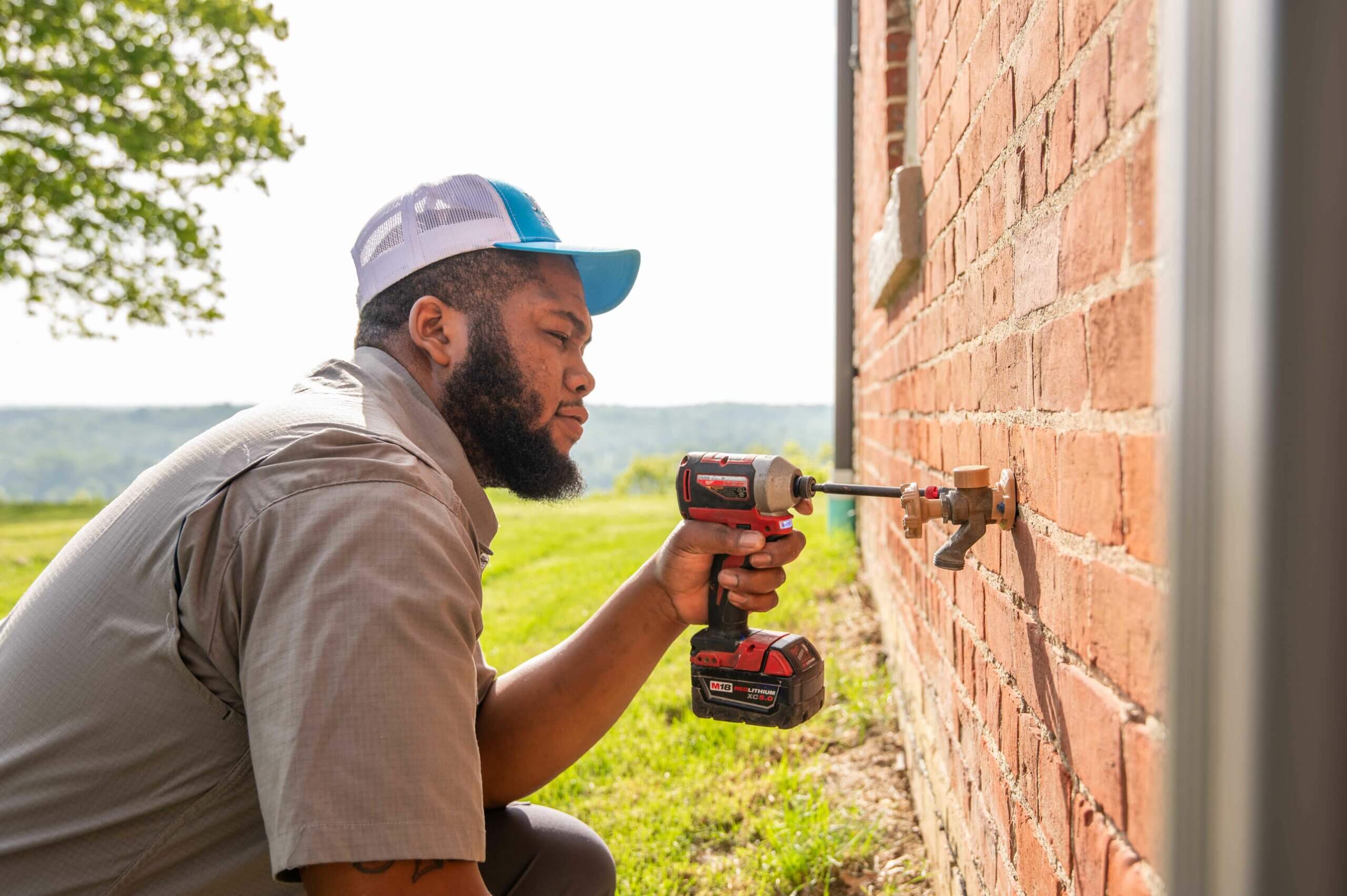 Jolly Drains Heating & Air technician installing a hot water spigot outside