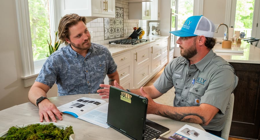 Jolly technician sitting down with a client at a table going over electrical panel replacement options.
