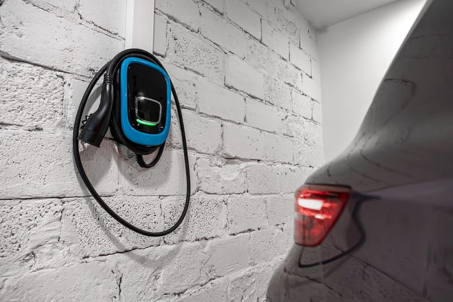 Electrical vehicle charger on white brick wall in garage.
