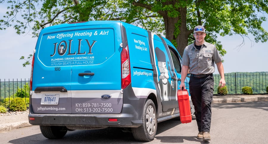 Jollly Plumbing technician walking with toolkit.