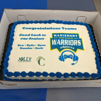 Congratulatory cake for Mariemont High School eSports with the Warriors logo, featuring 'Congratulations Teams' and 'Good Luck to our Seniors' along with the names Ben, Kylie, Ryan, Kander, and Zach.