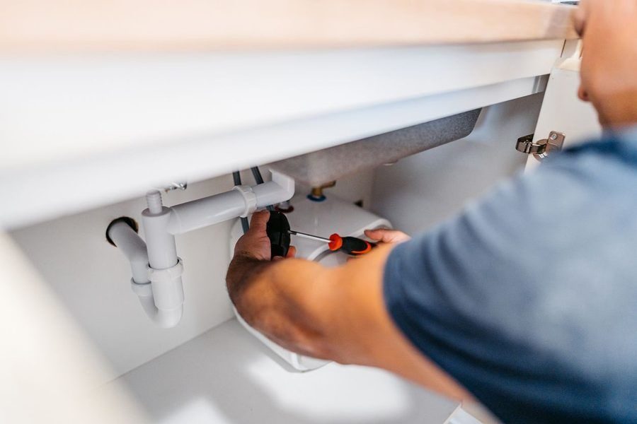 Plumber working on a sink pipe to clear out clog.