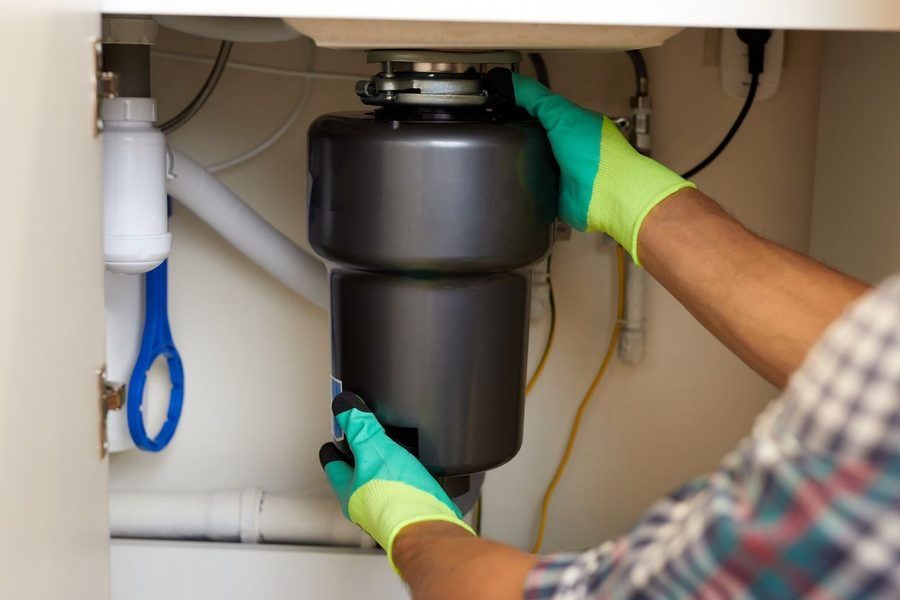 Local plumber inspecting and repairing home garbage disposal.
