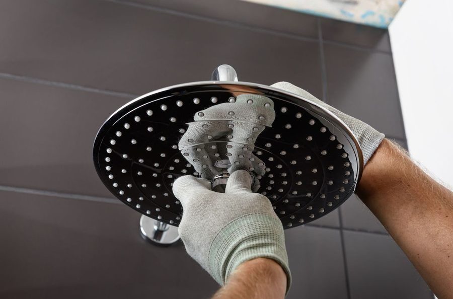 Plumber replacing the head of a shower in a home bathroom.