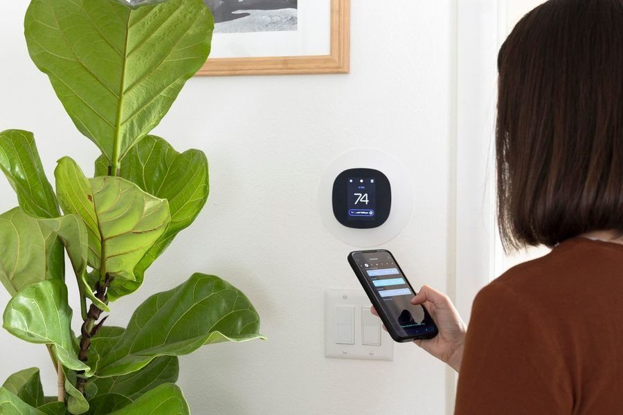 Homeowner syncing smartphone with new thermostat.