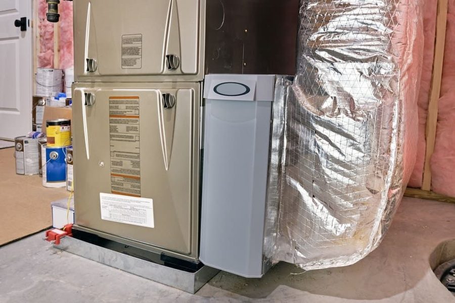 Furnace and air handler in a basement with foil-insulated ductwork and pink wall insulation nearby